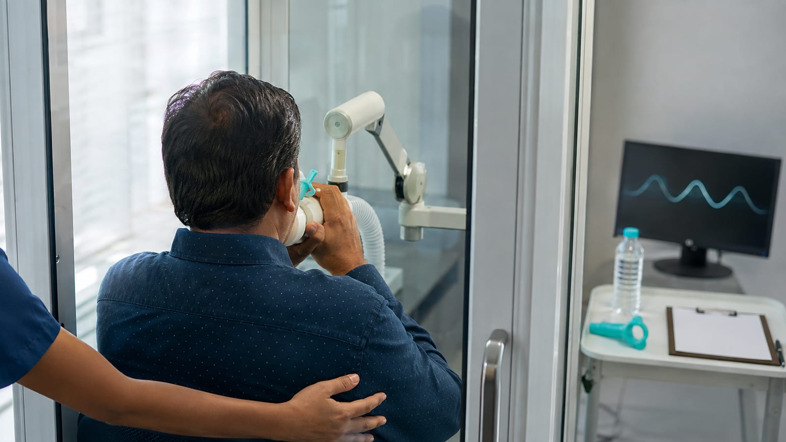 Patient undergoing pulmonary function testing with DLCO diffusion capacity measurement inside a modern PFT booth - the single most useful test after post-COVID lung damage at KIMS Electronic City